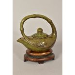 A 20TH CENTURY CARVED SERPENTINE DECORATIVE TEAPOT OF OVAL FORM, the scroll over handle of bamboo