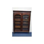 AN EDWARDIAN MAHOGANY DOUBLE DOOR BOOKCASE on turned legs with ceramic casters, width 130cm x