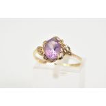 AN AMETHYST AND DIAMOND RING, the yellow metal ring with a central claw set oval cut amethyst,