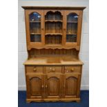 A MODERN PINE KITCHEN DRESSER, to top section with double glazed cupboard doors above a base with
