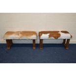 A PAIR OF RUSTIC RECTANGULAR STOOLS with animal hide seat covers, width 102cm x depth 42cm x