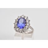 A MODERN LARGE TANZANITE AND DIAMOND OVAL CLUSTER RING, an oval mixed cut tanzanite measuring