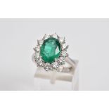AN 18CT WHITE GOLD MODERN LARGE EMERALD AND DIAMOND OVAL CLUSTER RING, an oval mixed cut emerald