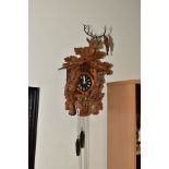 AN EARLY 20TH CENTURY BLACK FOREST CUCKOO CLOCK, with Stag's head carved to the leaf and gun
