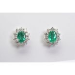 A MODERN PAIR OF EMERALD AND DIAMOND OVAL STUD EARRINGS, emeralds measuring approximately 6mm x 4mm,