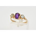 A 9CT GOLD THREE STONE RING, set with a central claw set oval amethyst, flanked by circular cut blue