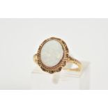 A 9CT GOLD OPAL RING, set with a central oval opal within a collet mount and scallop surround, to