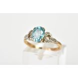 A 9CT GOLD TOPAZ RING, designed with a central oval claw set blue topaz with heart design openwork