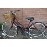 A BURGUNDY LADIES RALEIGH CAMEO BICYCLE with basket to front and pump