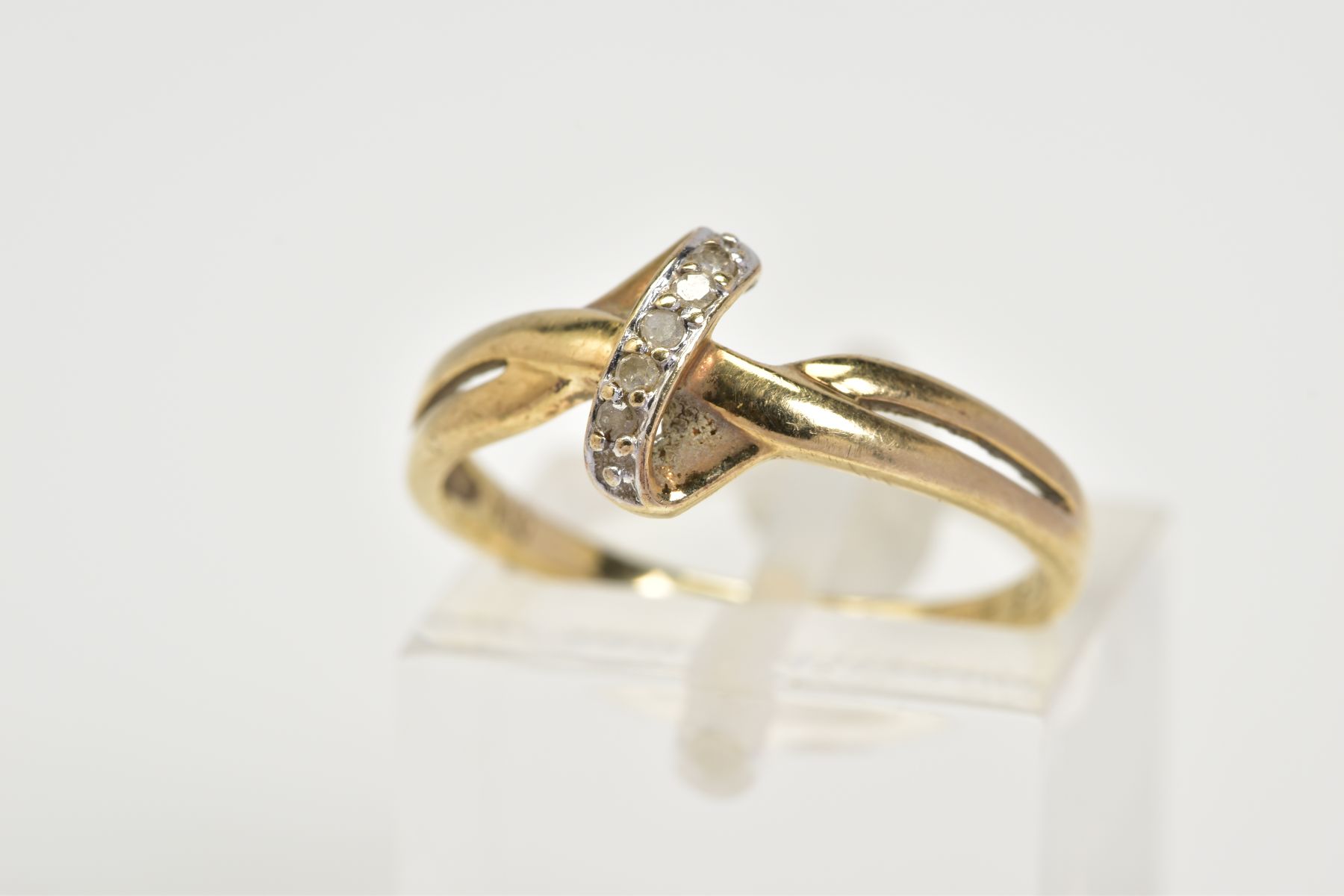 A 9CT GOLD DIAMOND SET RING, of crossover design set with a row of single cut diamonds, to the