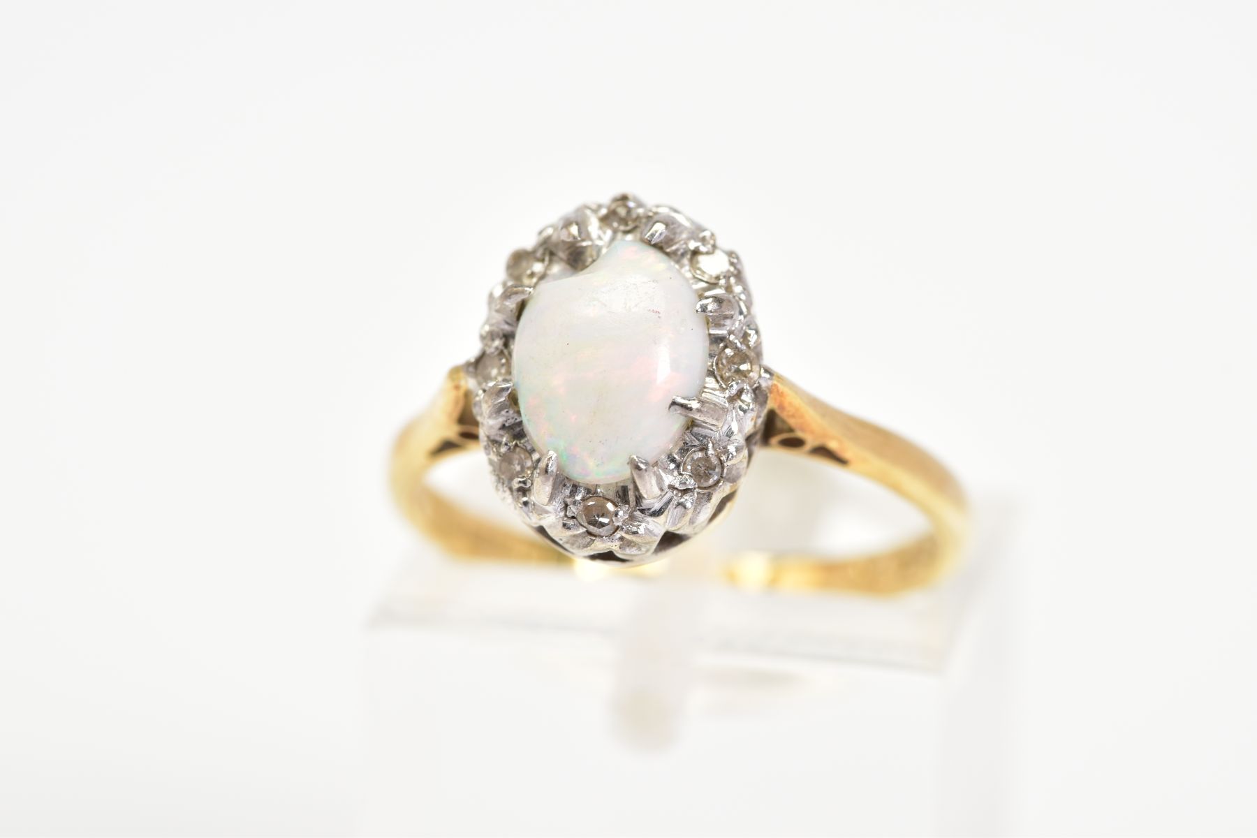 AN 18CT GOLD OPAL AND DIAMOND CLUSTER RING, a claw set central oval cabochon opal, with a single cut