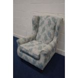 A FLORAL GREEN UPHOLSTERED WING BACK ARMCHAIR