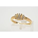 A DIAMOND SET RING, the yellow metal ring with a central design set with nine round brilliant cut