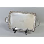 AN EDWARDIAN SILVER RECTANGULAR TWIN HANDLED TRAY, the handles and rim cast with gadrooning and