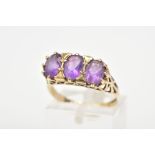 A 9CT GOLD AMETHYST RING, designed with three claw set oval cut amethyst, within a heart detail