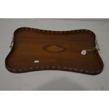 AN EDWARDIAN MAHOGANY SERPENTINE TRAY, with a stripped gallery, central shell inlay and twin brass