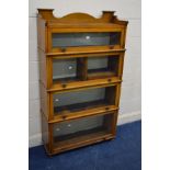 AN EARLY 20TH CENTURY ARTS AND CRAFTS OAK FOUR SECTION BOOKCASE, with glazed fall front doors, one