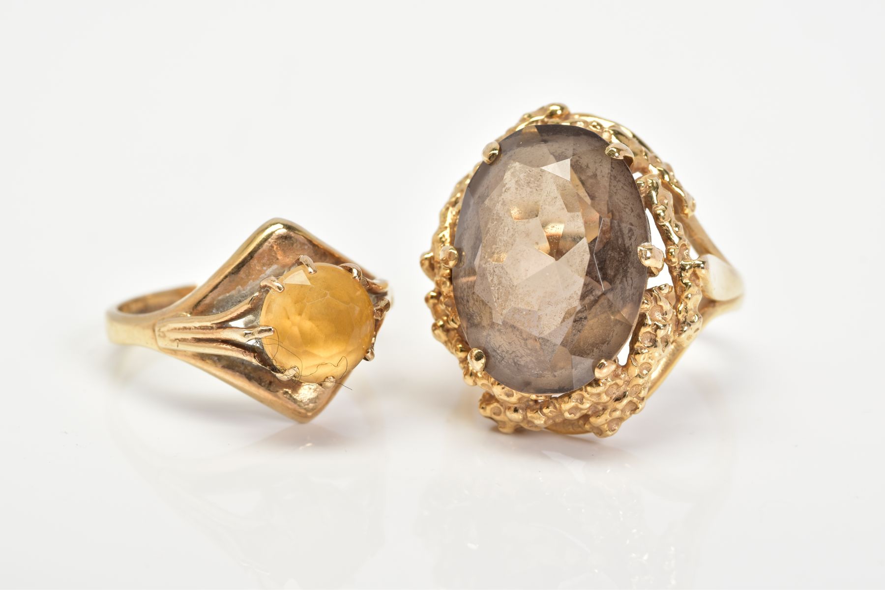 TWO 9CT GOLD GEM SET RINGS, the first ring designed with a claw set oval cut smokey quartz, within a