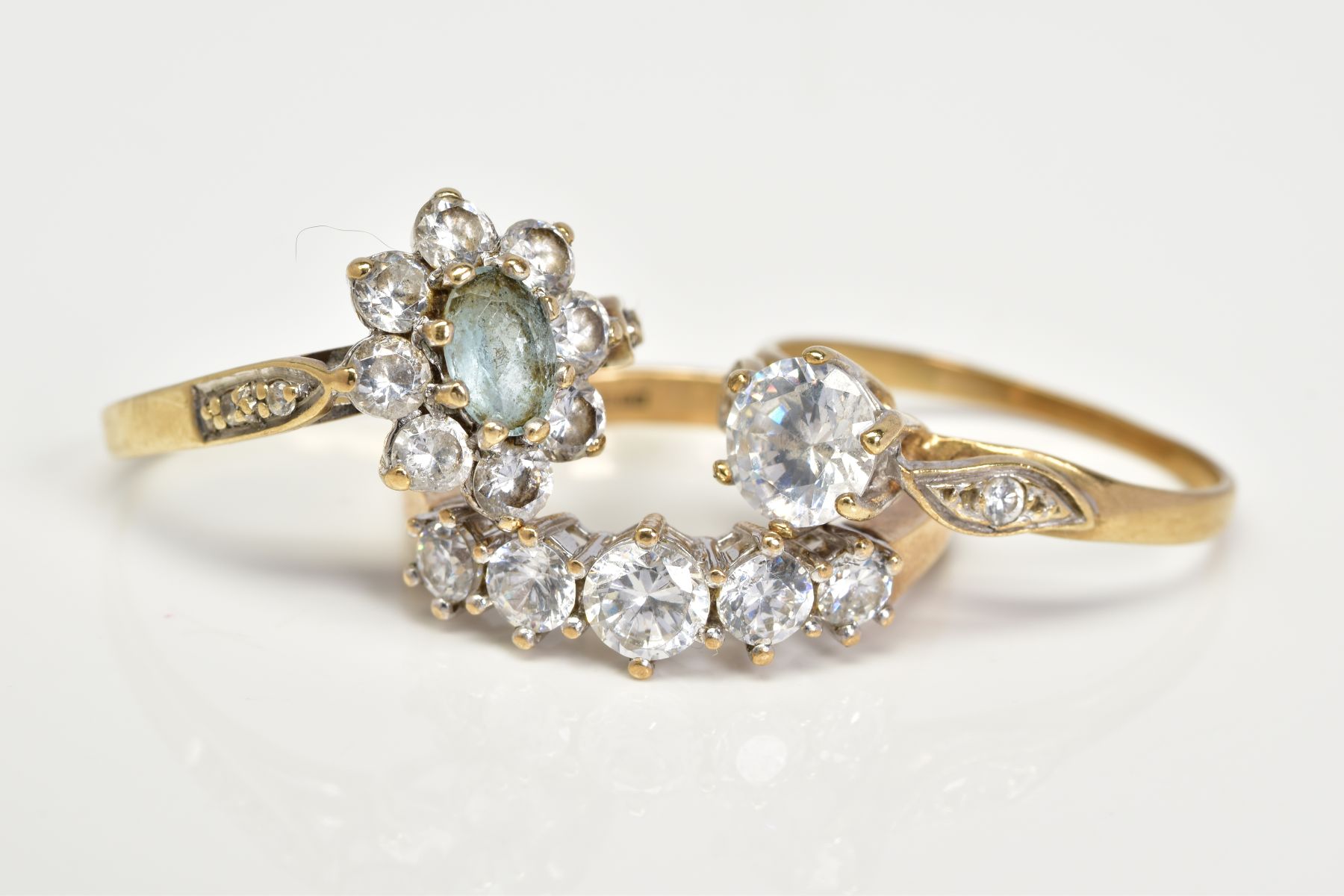 THREE 9CT GOLD GEM SET RINGS, the first designed as a cluster set with a central oval cut aquamarine