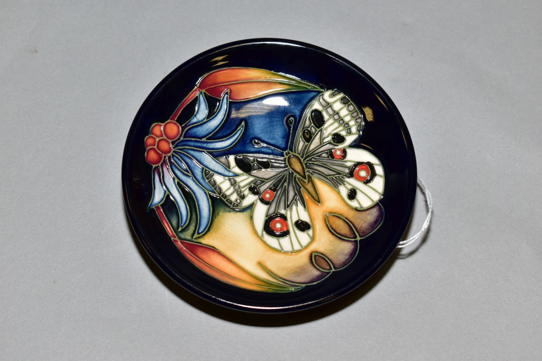 A 2005 MOORCROFT POTTERY PIN DISH, dark blue ground with the Apollo pattern, diameter 12cm, painted,