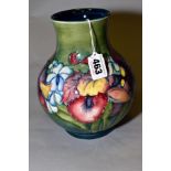 A MORRCROFT POTTERY BALUSTER VASE IN THE ORCHID AND SPRING FLOWERS PATTERN, on a green ground,