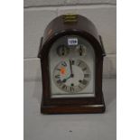 AN EARLY 20TH CENTURY OAK ARCHED TOP BRACKET CLOCK with silvered dial, pendulum and winding key,