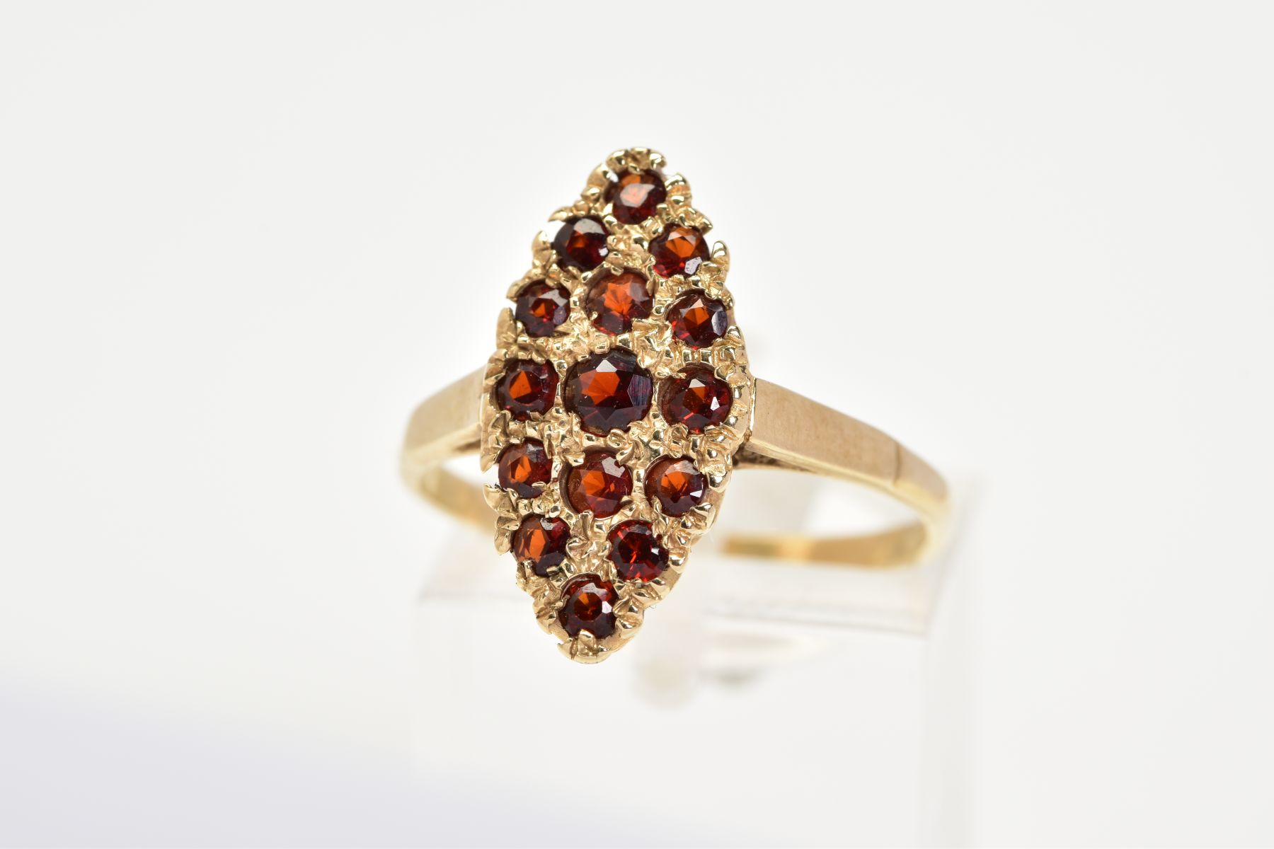 A 9CT GOLD GARNET RING, of lozenge set with fifteen circular cut garnets, to the plain polished