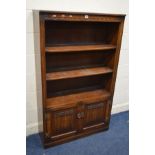 AN OLD CHARM OAK OPEN BOOKCASE, with two fixed shelves, above double linenfold cupboard doors, width