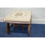 A LATE VICTORIAN WALNUT CROSS FRAMED FOOTSTOOL with needlework top, 52cm squared x height 41cm