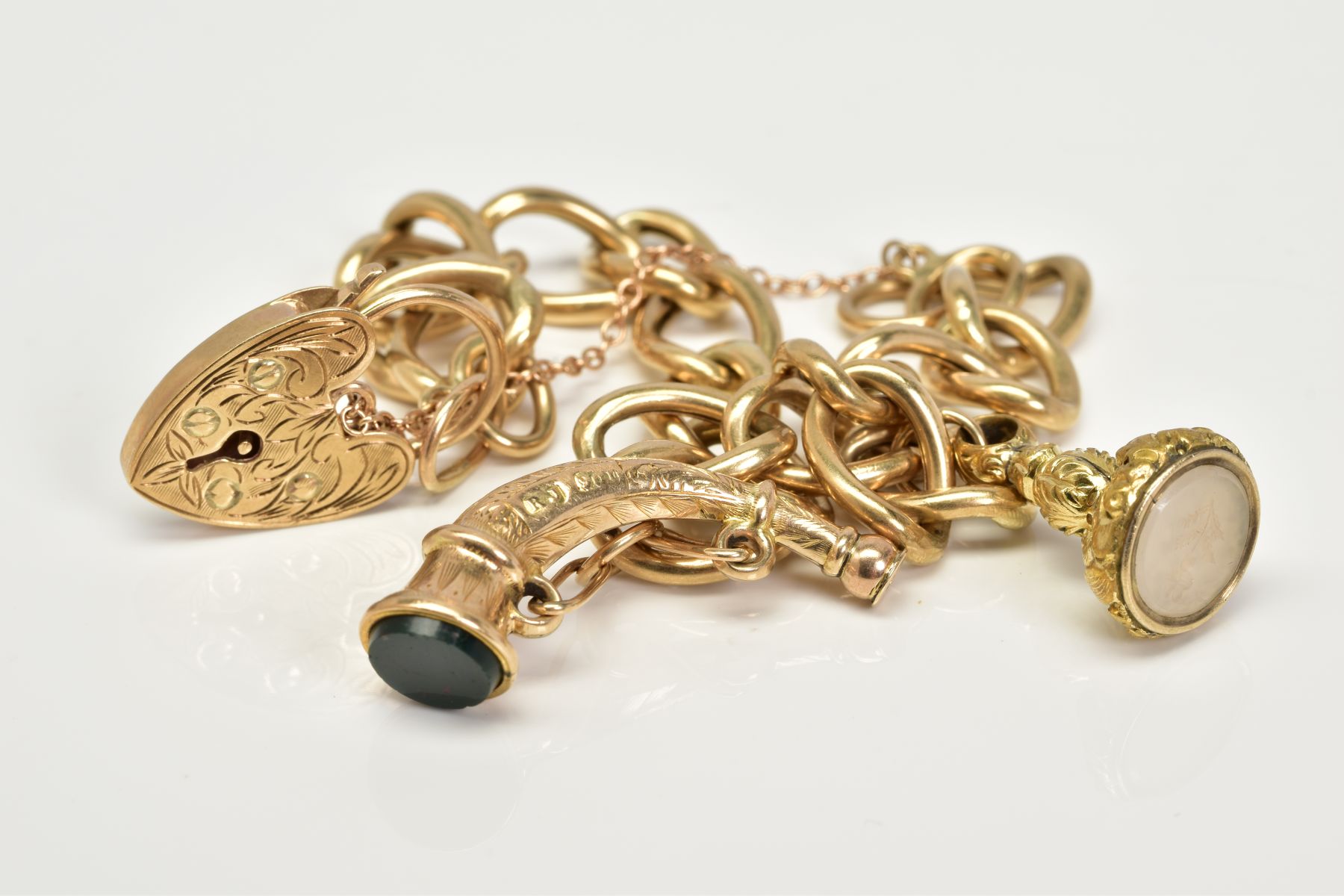 A 9CT GOLD CHARM BRACELET, the charm bracelet which suspends two charms, the first a fob seal