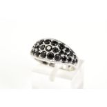 A GEM SET RING, the white metal ring designed with an oval panel set with circular cut black