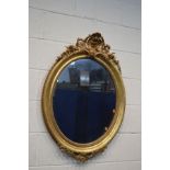 A 19TH CENTURY GILT FRAMED OVAL WALL MIRROR with gesso detailing to top and bottom edges and foliate
