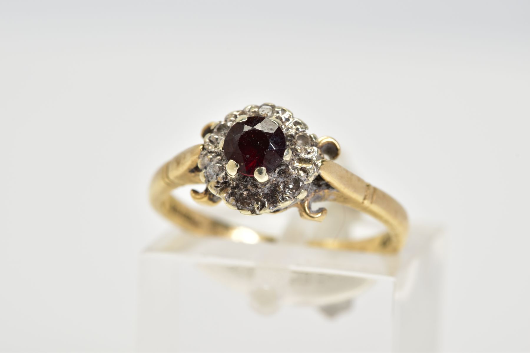 A 9CT GOLD GARNET AND DIAMOND CLUSTER RING, set with a central circular cut garnet with a round