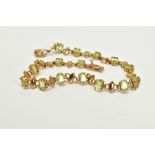 A 9CT GOLD PERIDOT LINE BRACELET, set with sixteen claw set oval cut peridots each interspaced