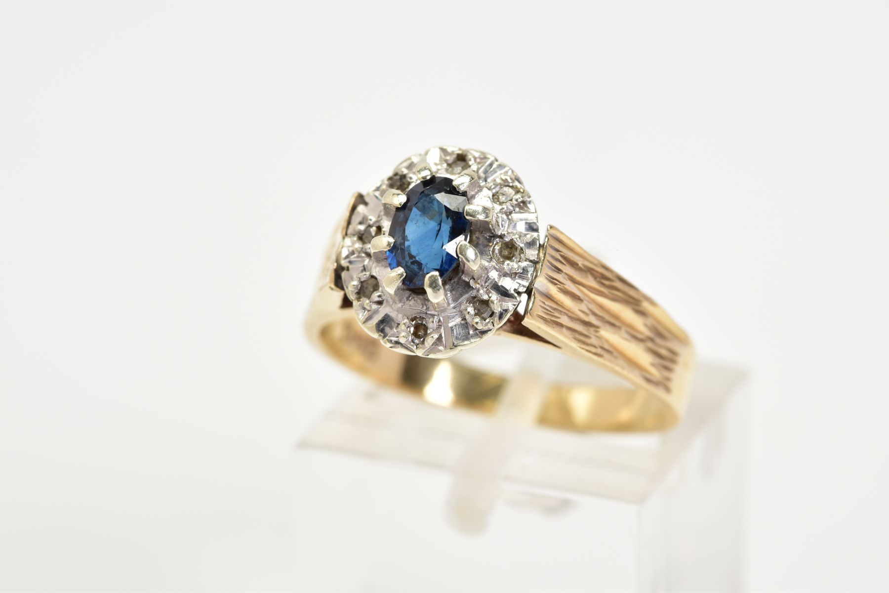 A 9CT GOLD SAPPHIRE AND DIAMOND RING, of a tiered cluster design with a central claw set oval cut