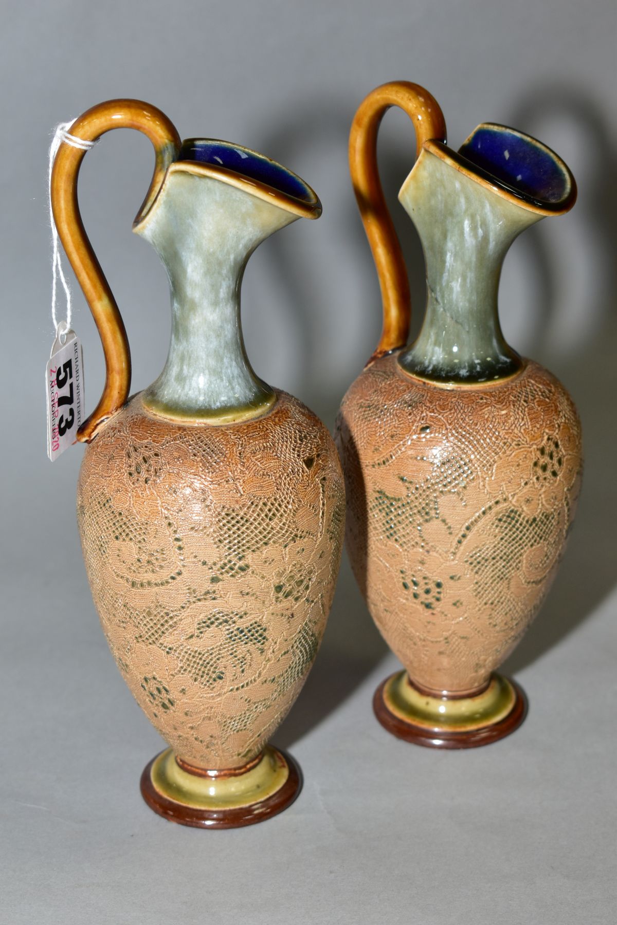 A PAIR OF ROYAL DOULTON STONEWARE EWERS, blue and brown glazed handle and spout, impressed lace