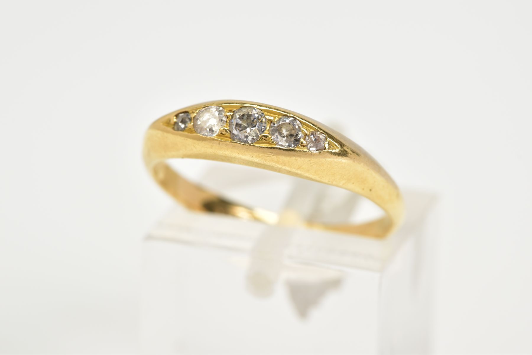 A YELLOW METAL DIAMOND BOAT RING, designed with five graduated diamonds with a central round