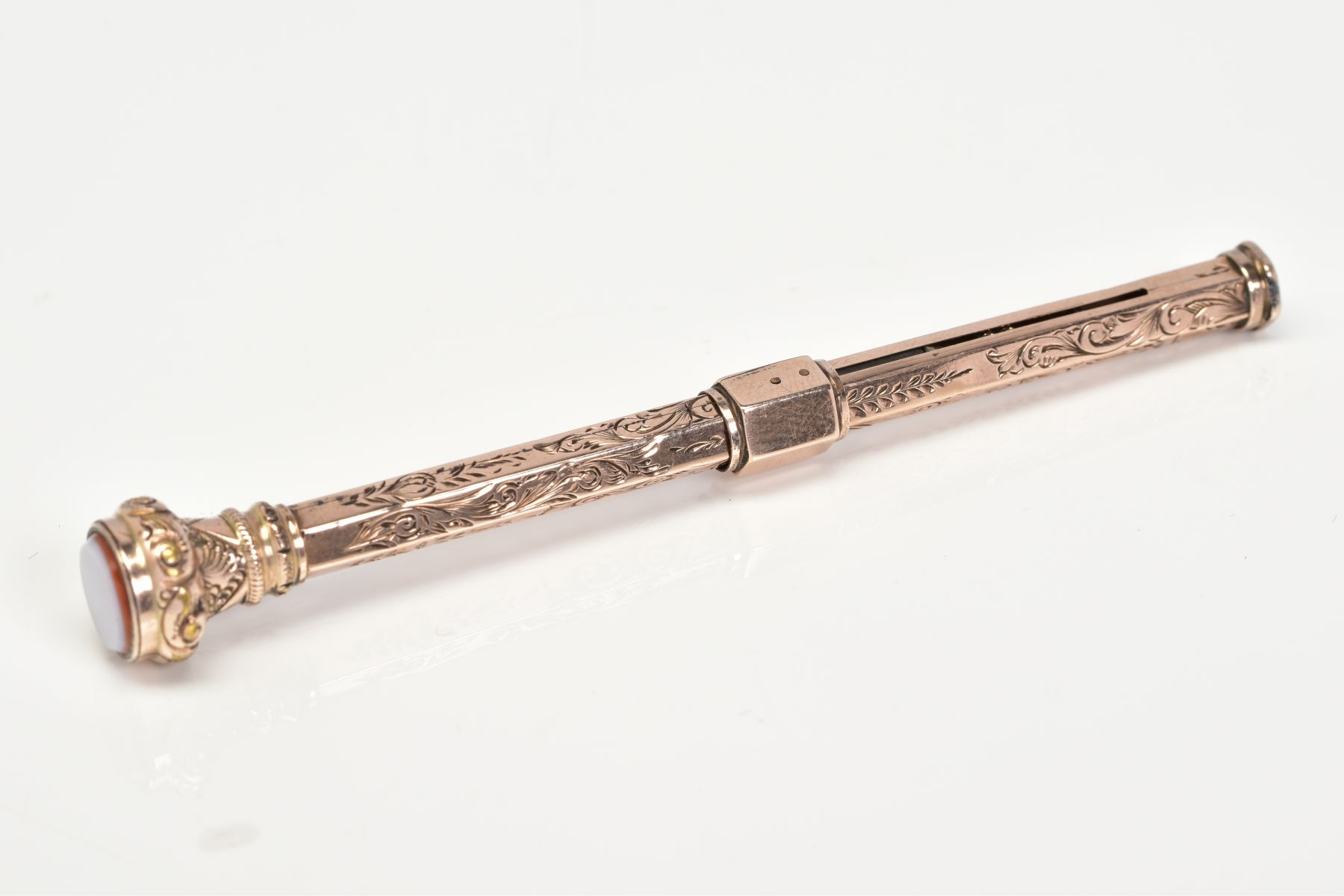 A YELLOW METAL RETRACTABLE PENCIL, designed with a floral engraved pattern to the body of the