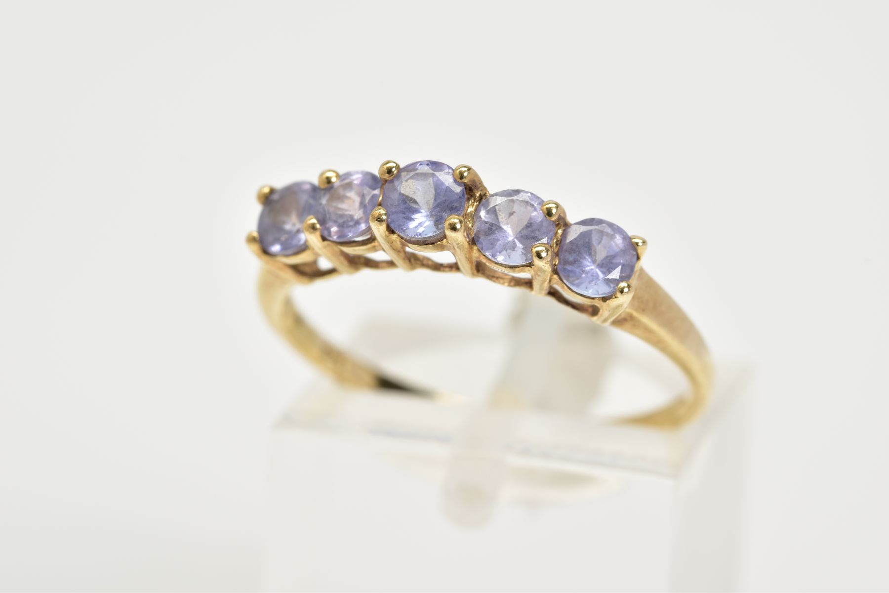 A 9CT GOLD FIVE STONE RING, of half hoop design set with five claw set circular cut amethyst, to the