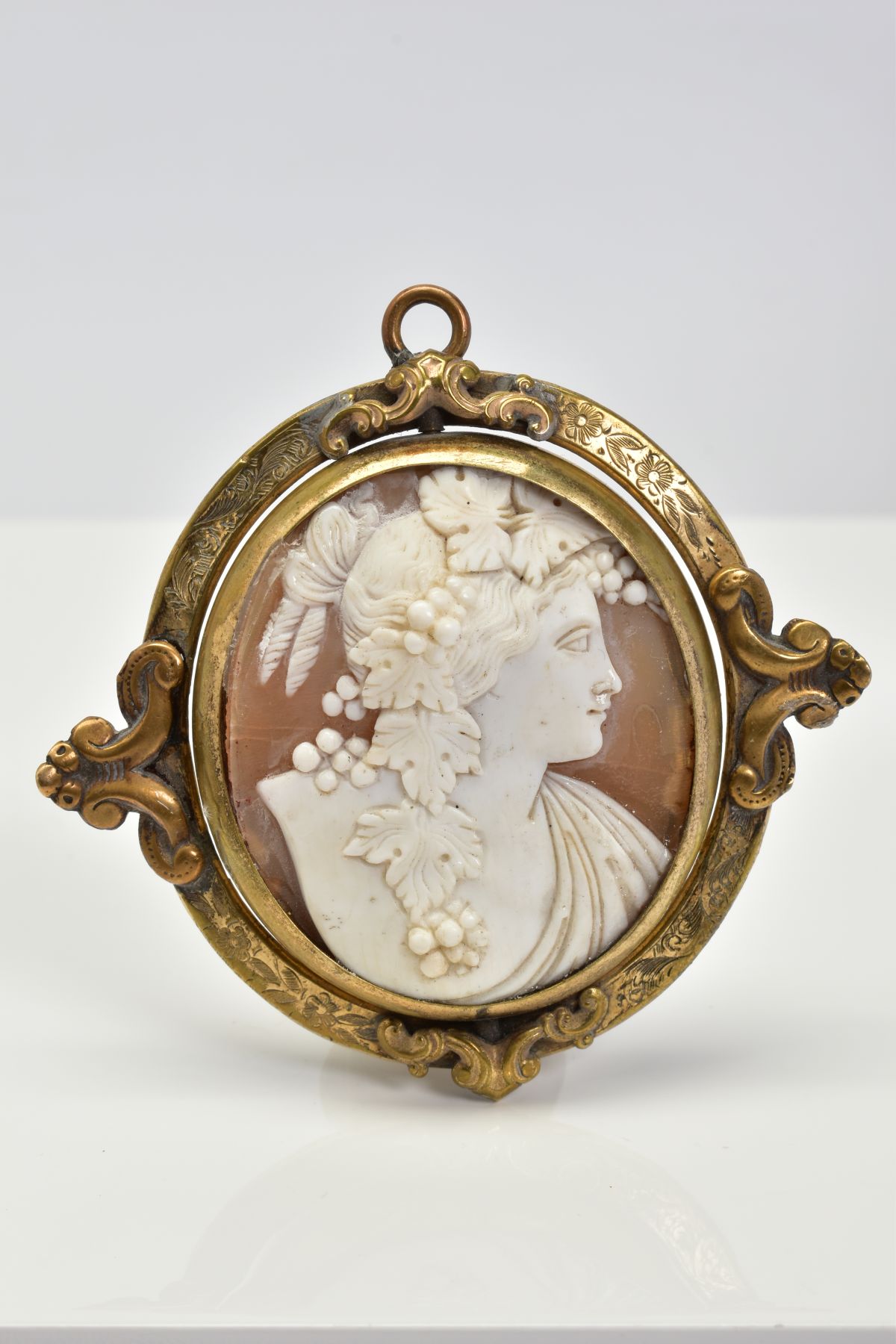 A YELLOW METAL SWIVEL MEMORIAL CAMEO PENDANT, the oval cameo panel depicting a lady in profile