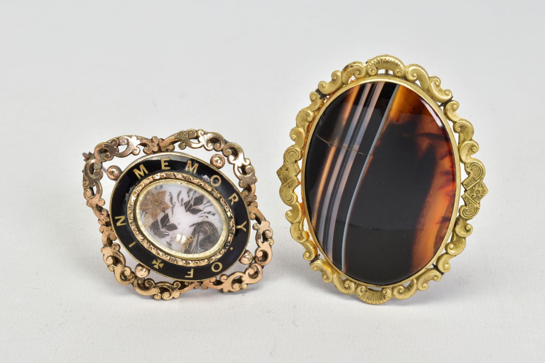 TWO VICTORIAN BROOCHES, to include a yellow metal mourning brooch, featuring an oval glass panel,