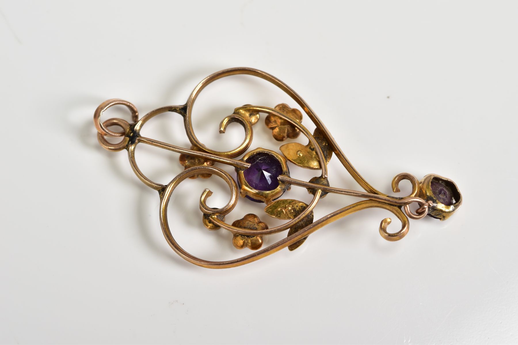 AN EDWARDIAN YELLOW METAL BROOCH, of openwork design, central panel set with a purple garnet - Image 2 of 2