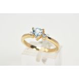 A 9CT GOLD TOPAZ AND DIAMOND RING, set with a central triangular cut blue topaz flanked with