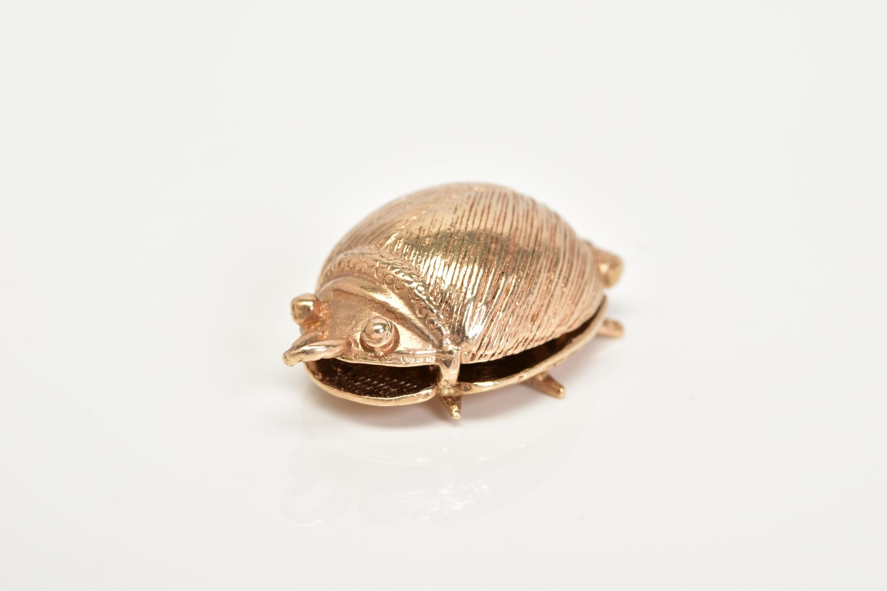 A 9CT GOLD BEATLES CHARM, in the form of a beetle opens to reveal four figures, John, Paul, Ringo