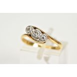 A YELLOW METAL THREE STONE DIAMOND RING, of cross over design with a central old cut diamond flanked