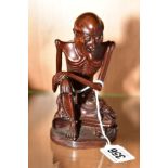 A JAPANESE HARDWOOD LAUGHING SEATED SKELETON with part paper label to base height 14cm