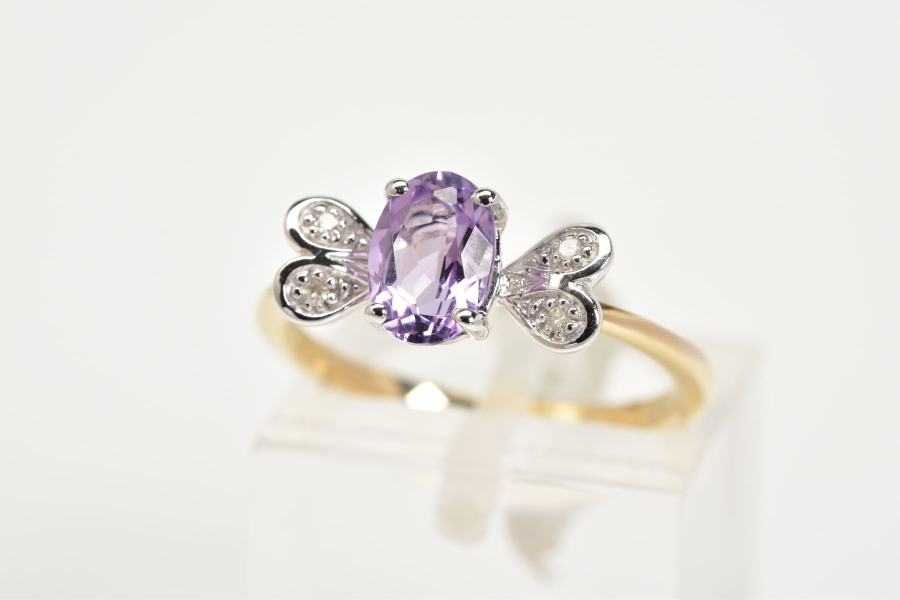 A 9CT GOLD AMETHYST AND DIAMOND RING, set with a central oval cut amethyst flanked with single cut