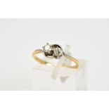 A YELLOW METAL DIAMOND RING, of crossover design set with two round brilliant cut diamonds, total
