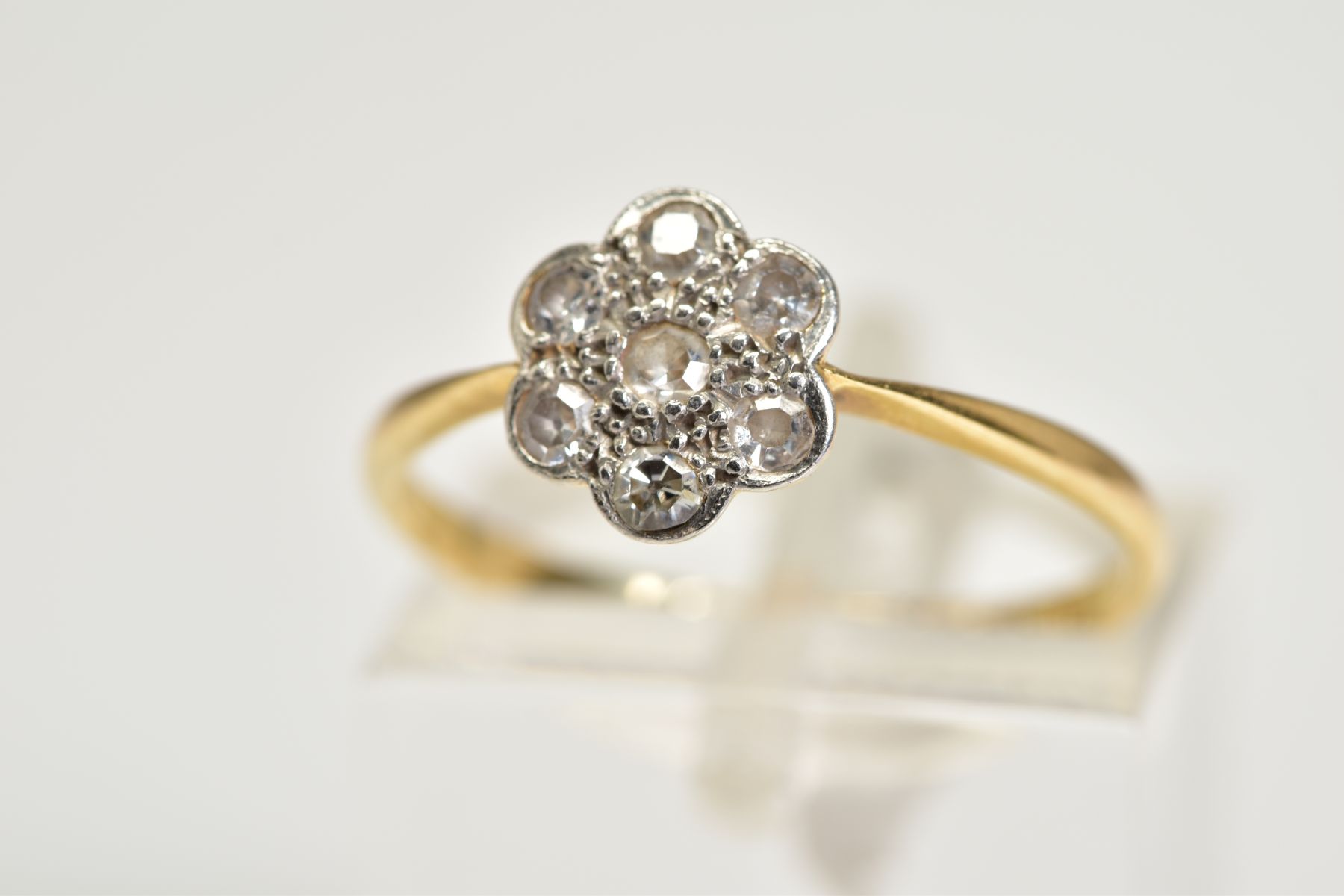 A DIAMOND CLUSTER RING, the yellow metal ring designed with a flower cluster set with single cut