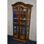 A TALL MODERN OAK TWO DOOR DISPLAY CABINET with bevelled glass panels, internal lighting and five